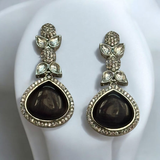 American Diamond Black Partywear Earrings with teardrop black stones and intricate leaf-shaped studded accents displayed on a white jewellery display stand.