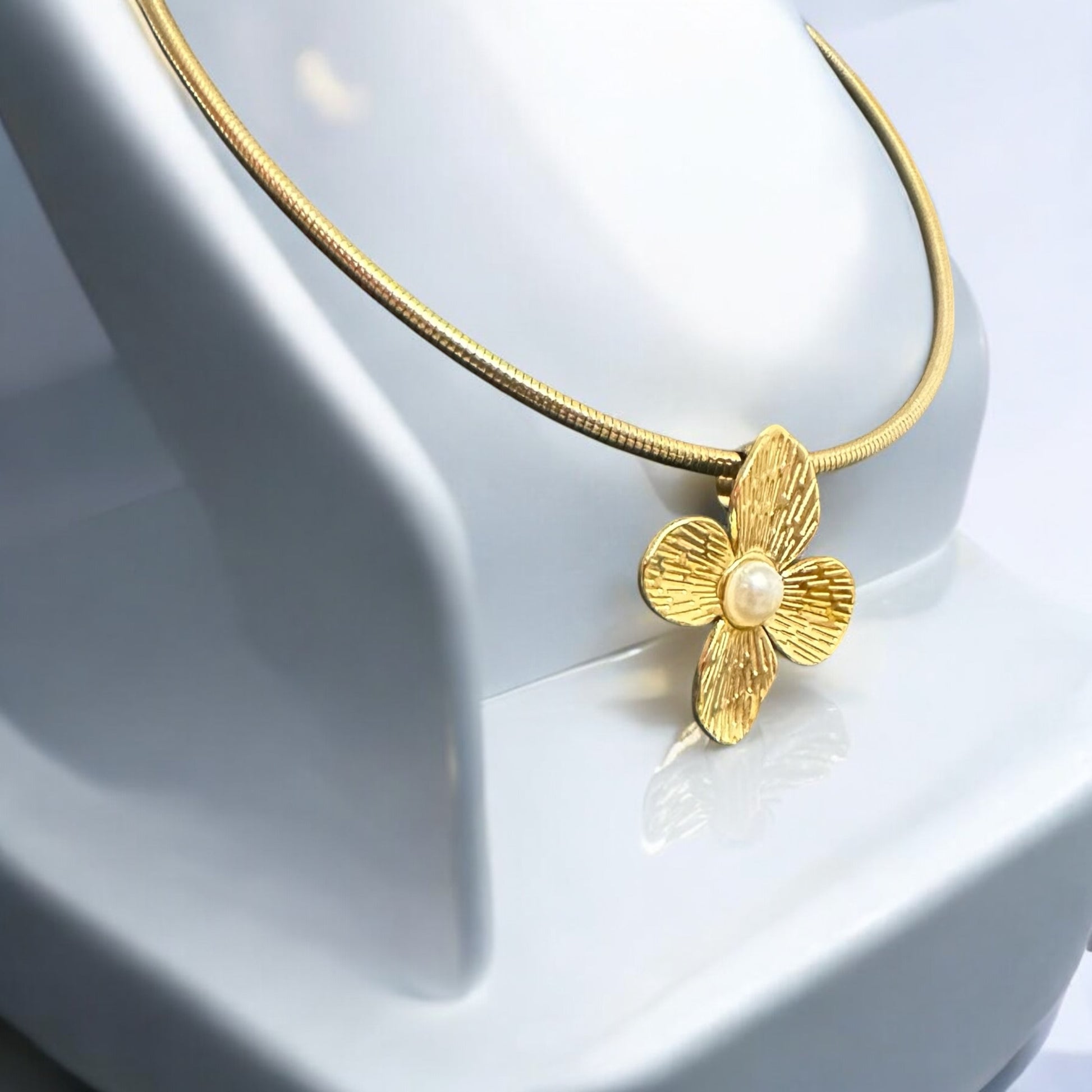 Elegant Anti-Tarnish Flower Necklace with a gold-tone floral pendant and pearl centerpiece on a sleek gold chain placed on a white jewellery display stand.