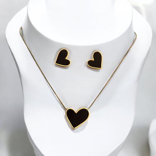 Anti-tarnish heart-shaped pendant set in gold finish with matching earrings placed on a white colored jewellery display stand.