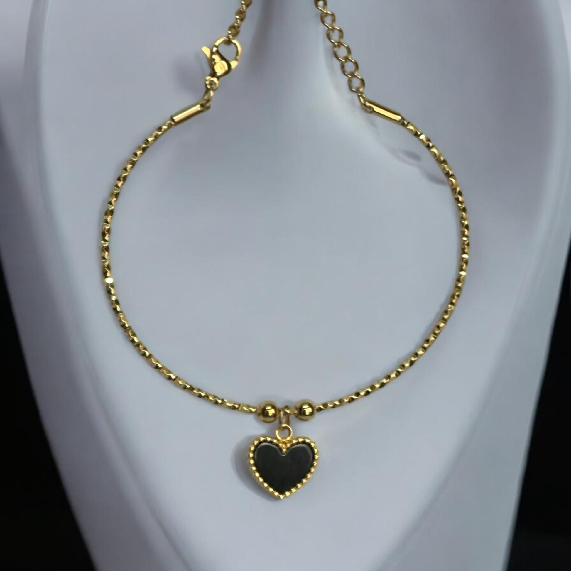 Anti-Tarnish Heart Shape Charm Bracelet in Gold Finish with Black Heart Pendant placed on a jewellery display stand.