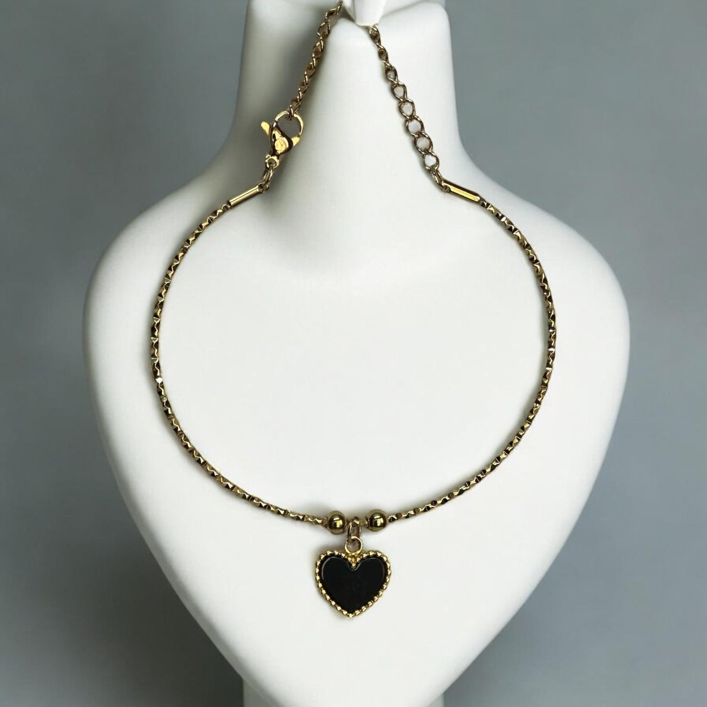 Anti-Tarnish Heart Shape Charm Bracelet in Gold Finish with Black Heart Pendant placed on a jewellery display stand.