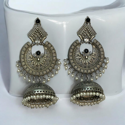 Apala Polish Silver Statement Earrings with Intricate Jhumki Design and Pearl Detailing placed on a white coloured jewellery display stand.