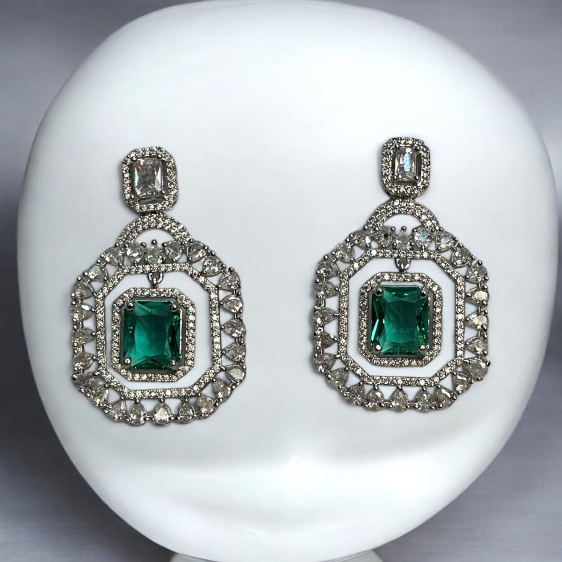 Beautiful Statement American Diamond Earrings – bold geometric earrings with sparkling American diamonds and emerald-green centerpiece stones. Perfect for weddings and festive occasions.