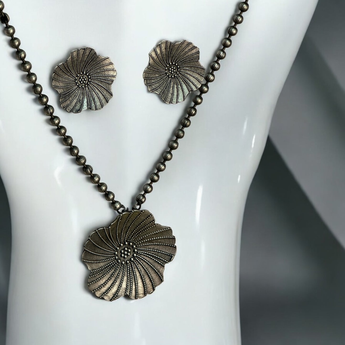 German silver chain pendant set featuring a large floral design pendant with intricate dotted detailing, paired with matching floral earrings. Displayed against a white background on a mannequin bust.