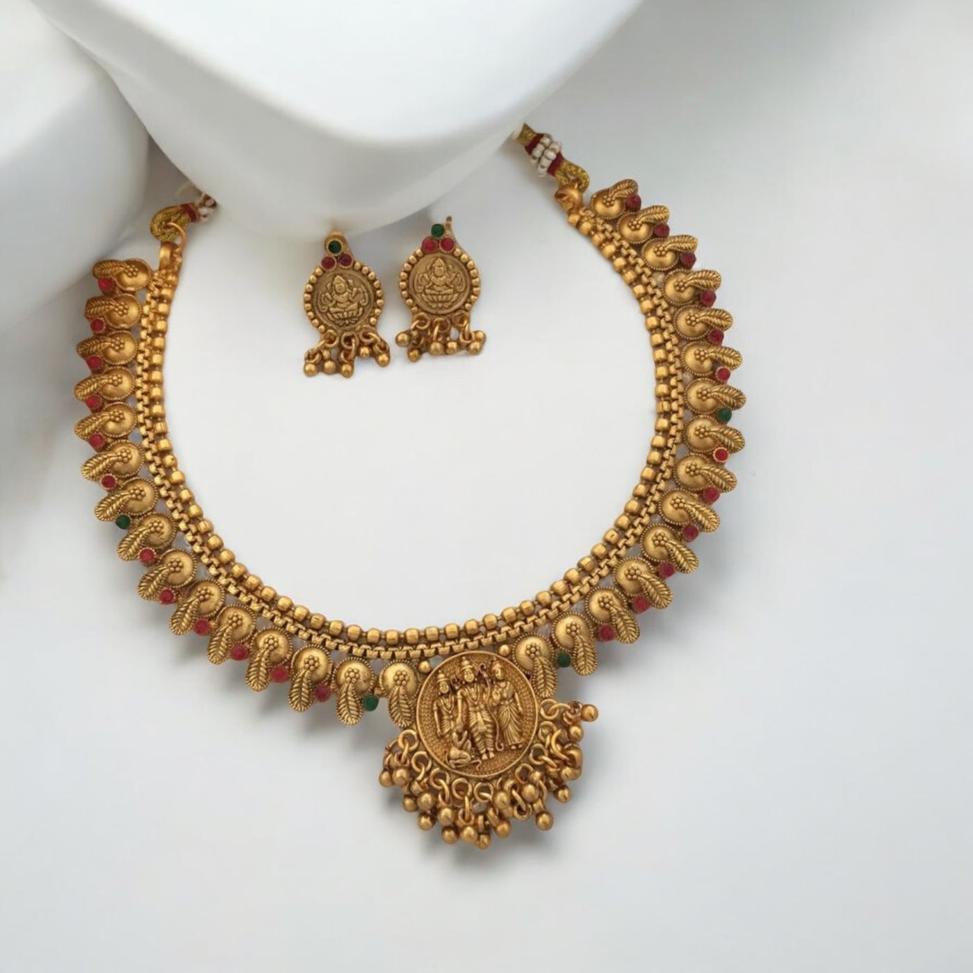 Gold-Plated Ram Darbar Temple Necklace with Earrings – traditional gold-tone necklace featuring a detailed Ram Darbar motif, paisley designs, and red-green enamel accents. A heritage-inspired set for festive and wedding occasions.