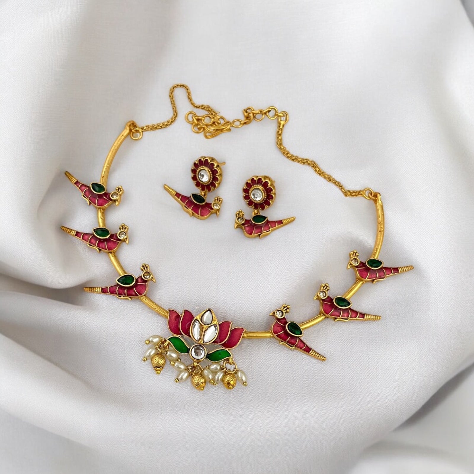 Temple Necklace in Hasli Design – traditional gold-tone hasli-style necklace with red and green enamel detailing, lotus centerpiece, pearl drops, and matching earrings. Ideal for festive and wedding wear.