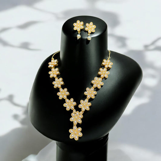 Gold-tone flower design necklace adorned with pearls, elegantly displayed on a black bust. Matching floral earrings with pearl drops complete the set, perfect for adding grace to your outfit.