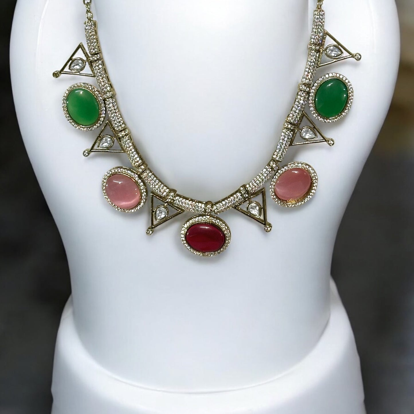 Premium Moissanite Diamond Multicolour Necklace with red, green and pink stones embedded. It is placed on a white jewellery display stand.