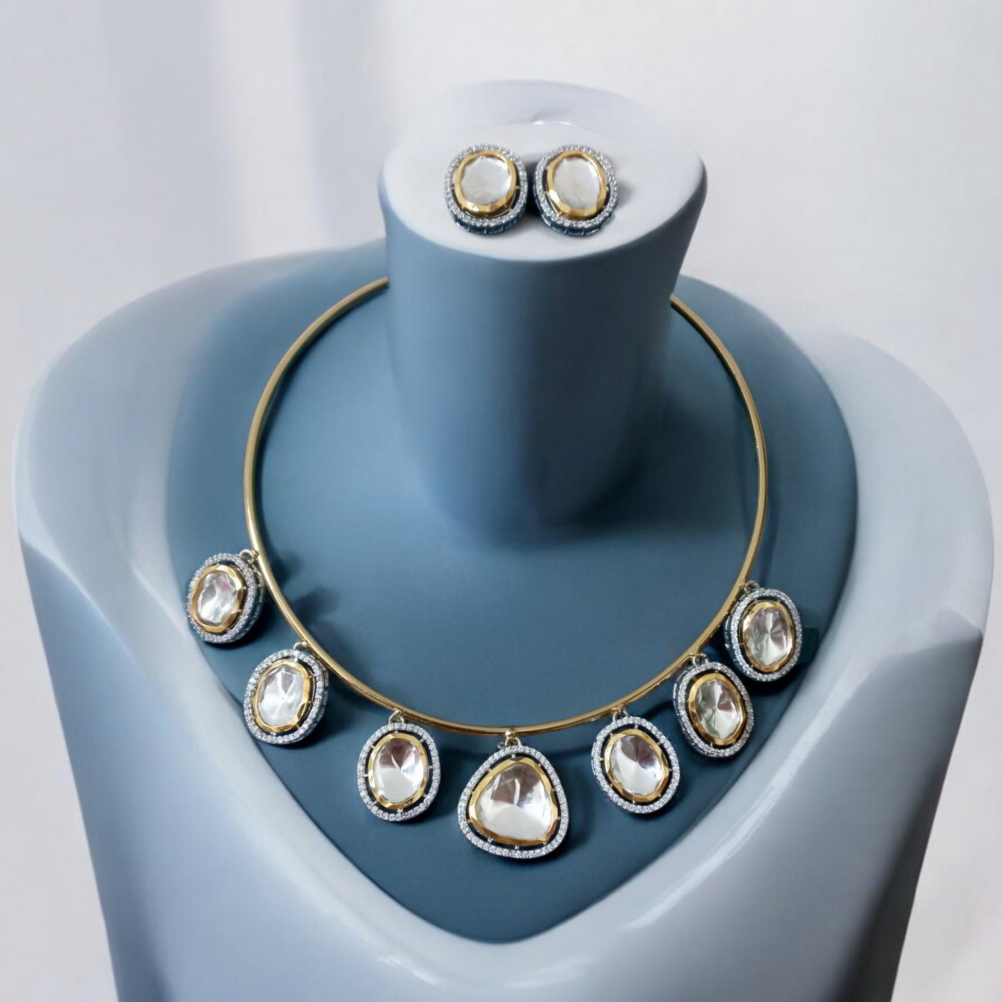 Premium Polki Kundan hasli-style necklace with radiant stones and matching earrings, displayed elegantly on a blue velvet jewellery display stand.