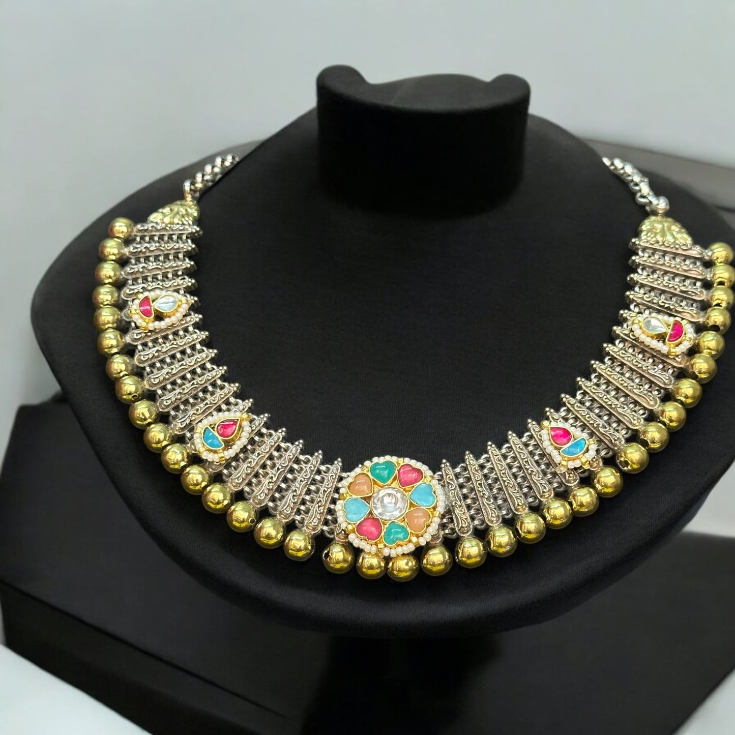 Premium silver replica kundan pachi necklace featuring colorful stone detailing and traditional design, displayed on a black bust stand.