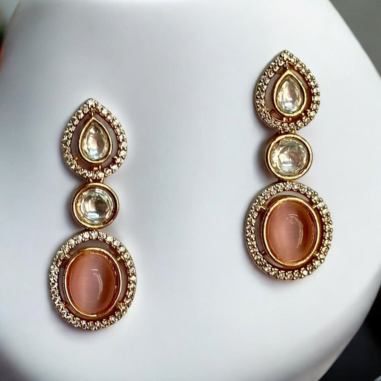 Premium Polki Kundan earrings featuring an elegant gold-tone design with intricate Polki stones, placed on a white coloured jewellery display stand. Available with its necklace in set on our bella & Diva website