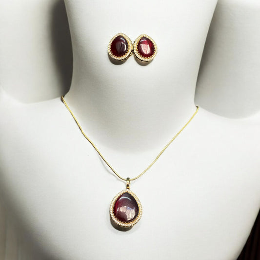 Red Monalisa Pendant Set adorned with American Diamonds, featuring a bold centerpiece and matching stud earrings placed on a white coloured jewellery display stand.