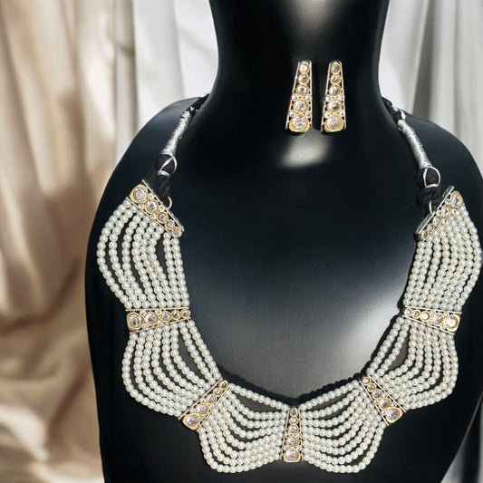 Royal Pearl Necklace Set featuring multiple layers of pearls with silver-tone accents and matching earrings, displayed on a black bust against a soft golden drape backdrop.