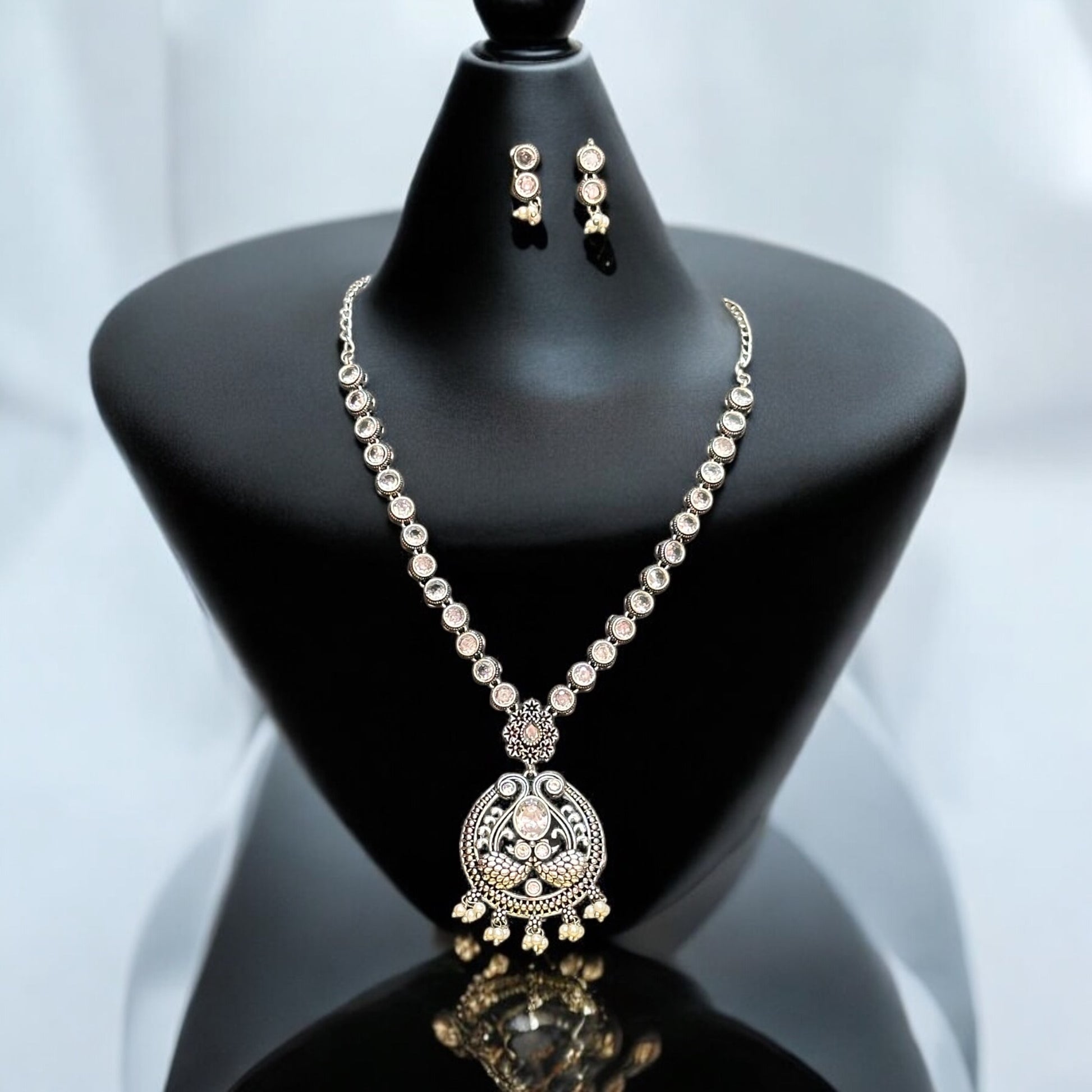 Exquisite Silver Replica Necklace Set with Earrings featuring intricate detailing and traditional craftsmanship. It is placed on a black jewellery display stand.