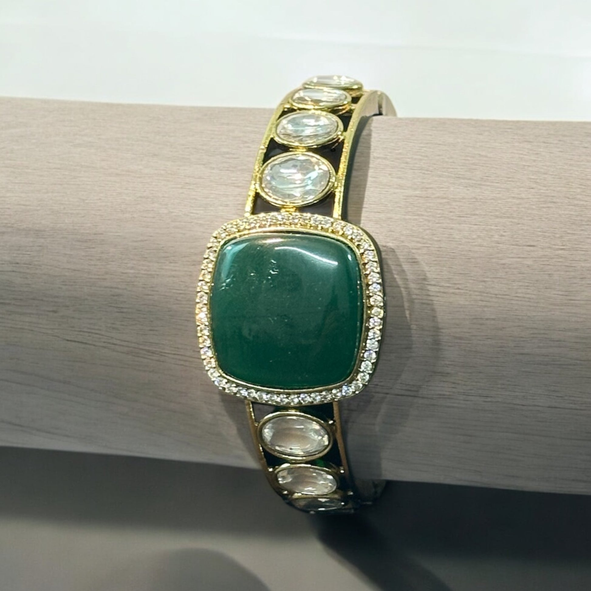 Single Kada With Green Doublet Stone Polki Kundan Bracelet rolled in a wooden stand.