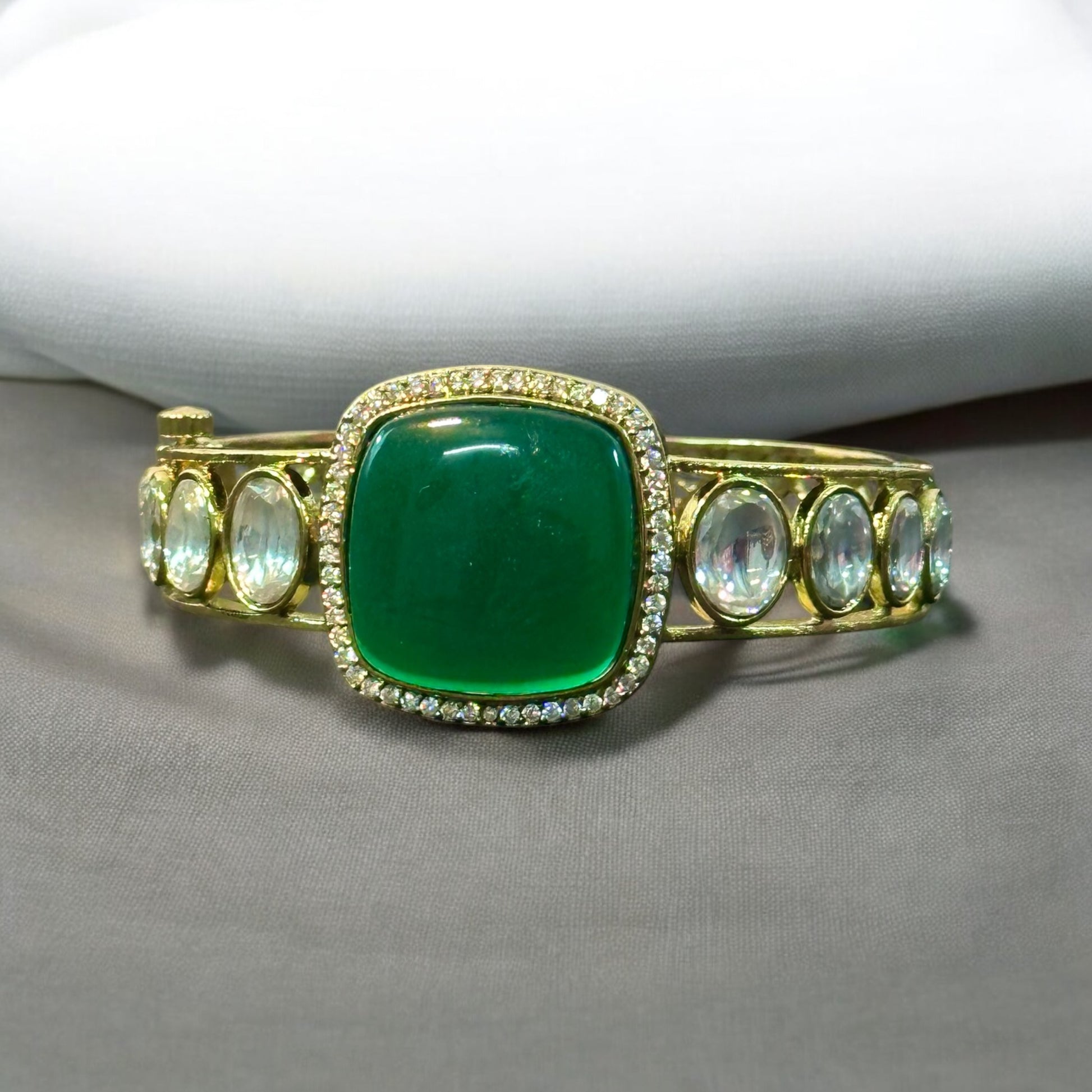 Single Kada With Green Doublet Stone Polki Kundan Bracelet placed on a grey fabric with white background.