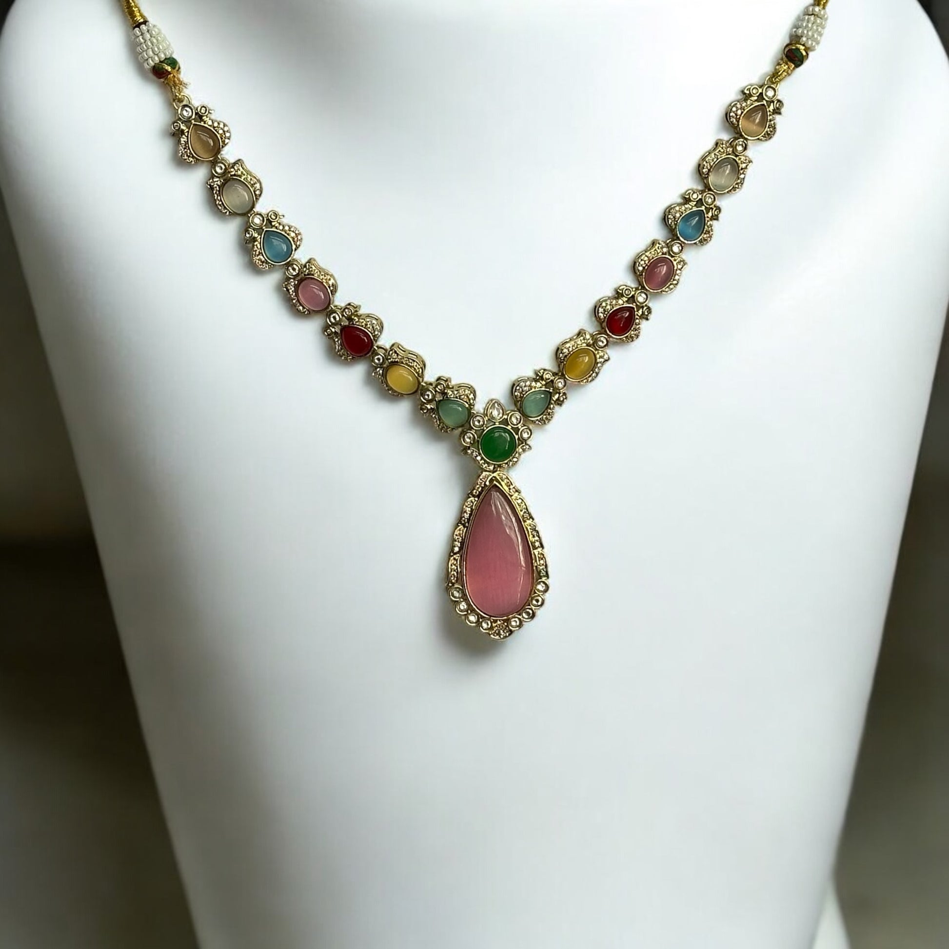 Statement Multicolor Polki Kundan Necklace placed on a white coloured jewellery display stand. The polki kundan necklace is featuring a colorful design with intricate Kundan work and bold pink accents.