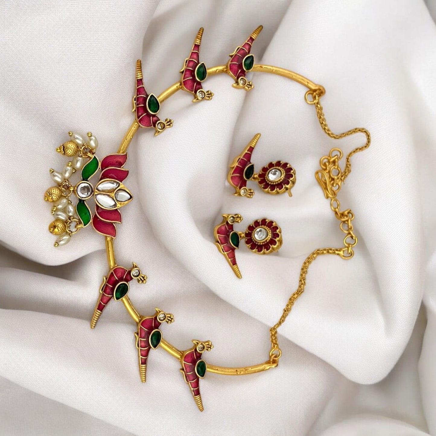 Temple Necklace in Hasli Design – traditional gold-tone hasli-style necklace with red and green enamel detailing, lotus centerpiece, pearl drops, and matching earrings. Ideal for festive and wedding wear.