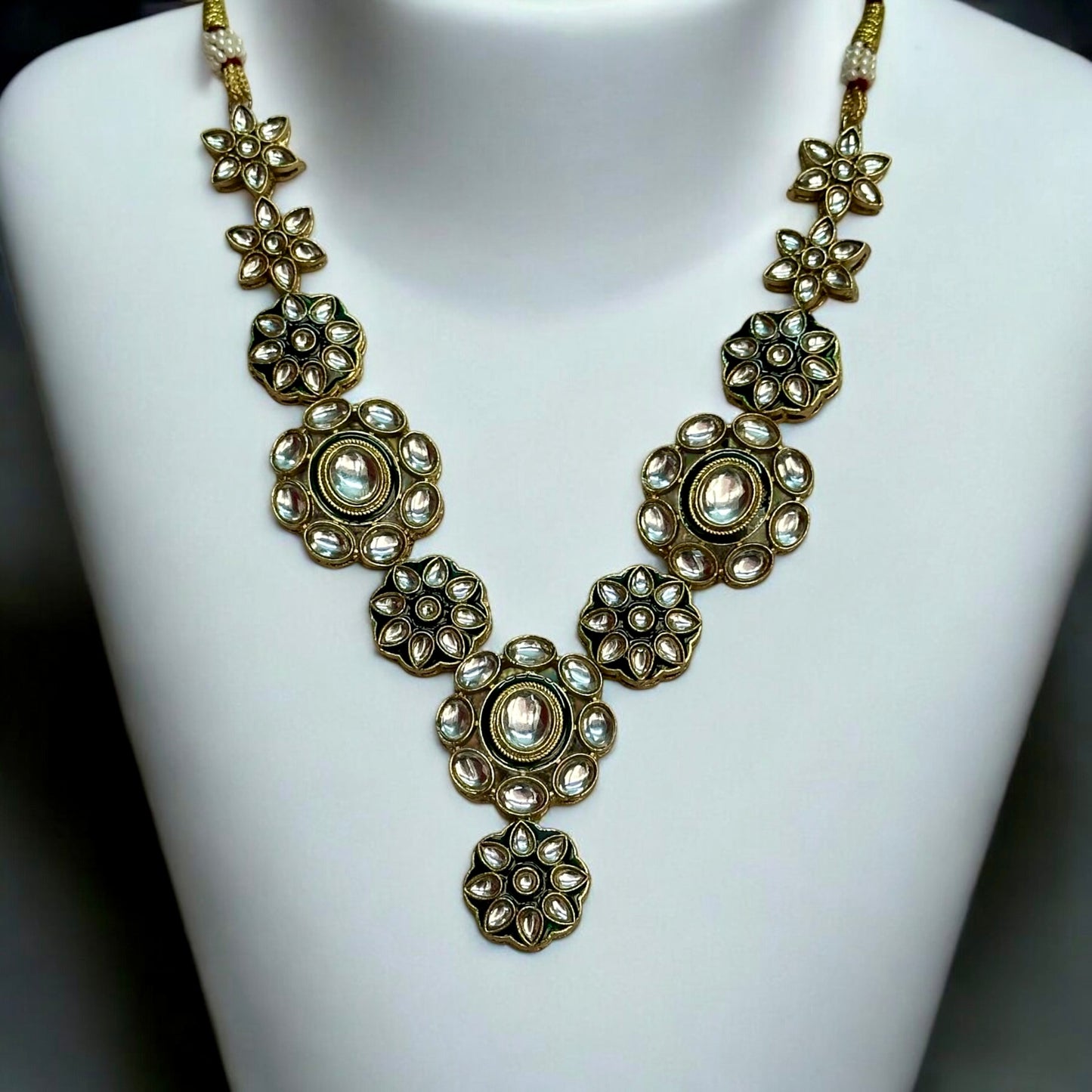 Elegant Kundan necklace featuring intricate floral designs in green and gold tones, placed on a white coloured jewellery display stand. These are perfect for traditional and festive occasions. Now available on bellandiva.com.