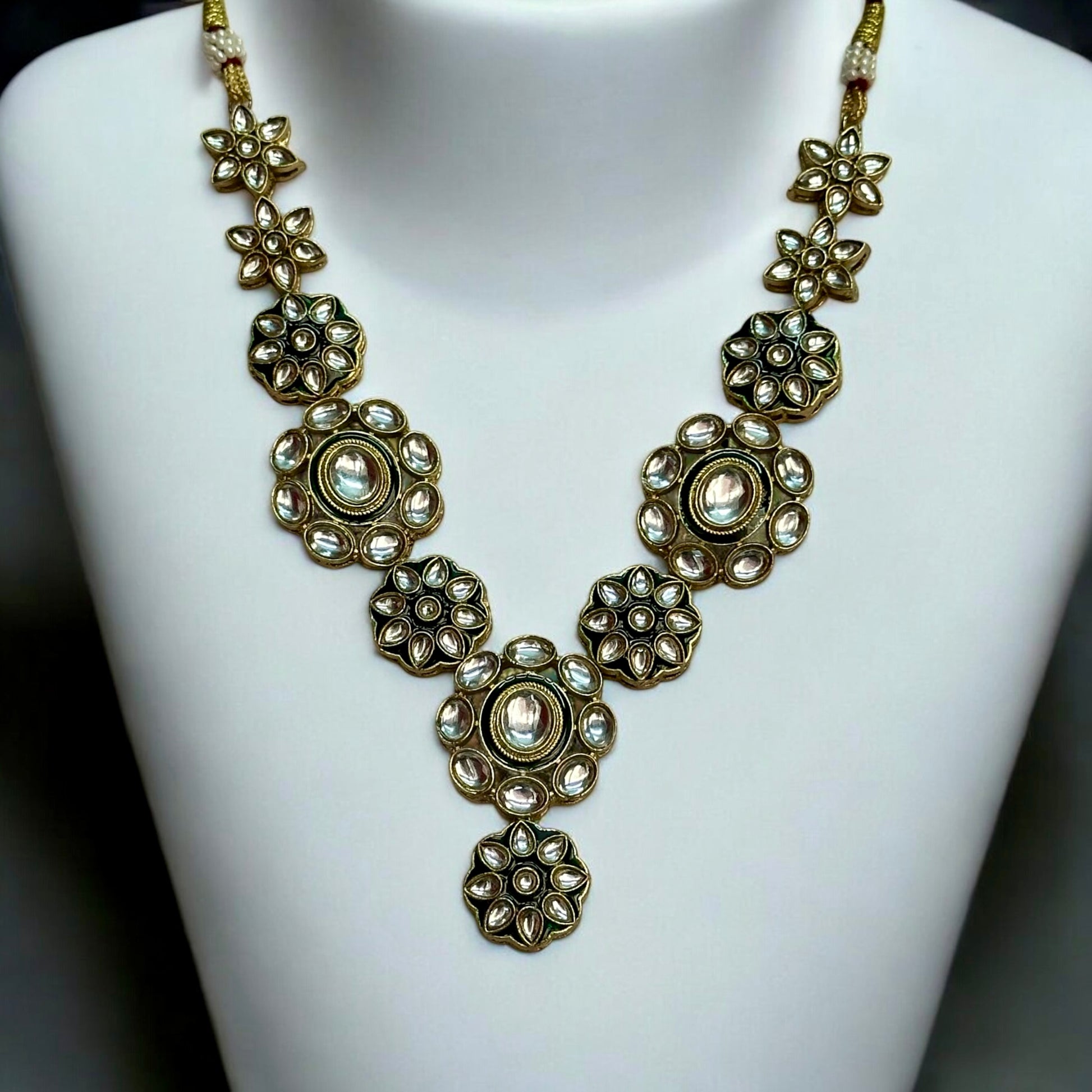 Elegant Kundan necklace featuring intricate floral designs in green and gold tones, placed on a white coloured jewellery display stand. These are perfect for traditional and festive occasions. Now available on bellandiva.com.